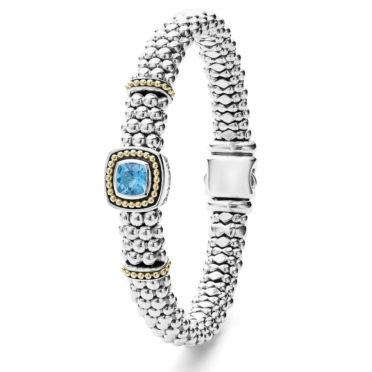 A sterling silver & 18k gold bracelet standing vertically in the middle of a white background featuring a Swiss blue topaz gemstone and sterling silver Caviar beading with 18K gold detailing.