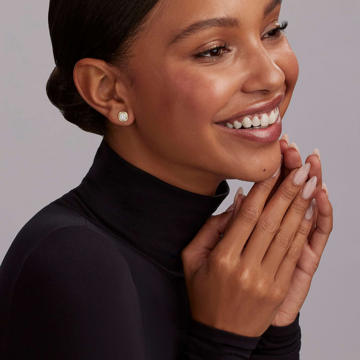 A woman is wearing a black turtleneck and a pair of two-toned stud earrings surrounded by 18K gold Caviar beading and smooth sterling silver. 