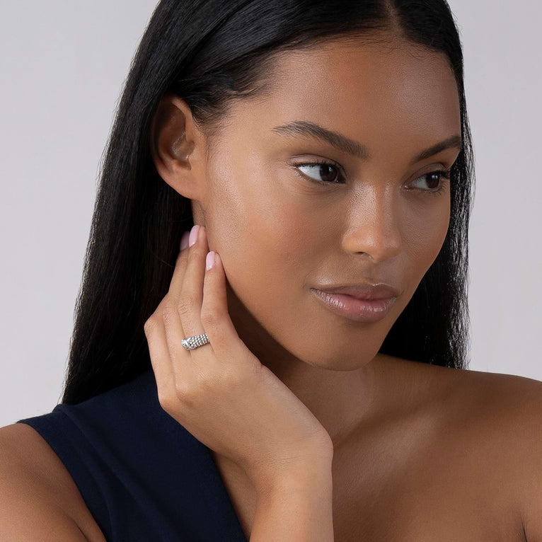 A woman wearing a sterling silver ring featuring an x motif and silver Caviar beading