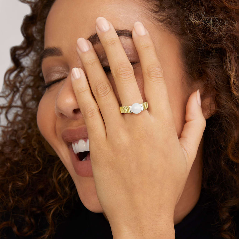 A man is wearing a sterling silver and 18k gold ring featuring a cultured freshwater pearl and caviar beading. 