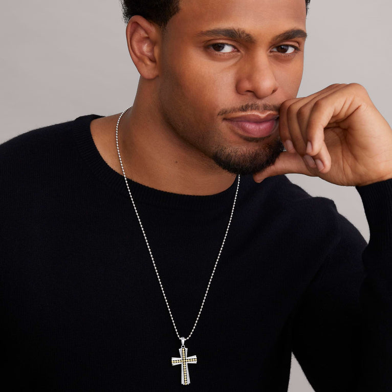 A man wearing a two-tone caviar beaded cross amulet with a chain necklace