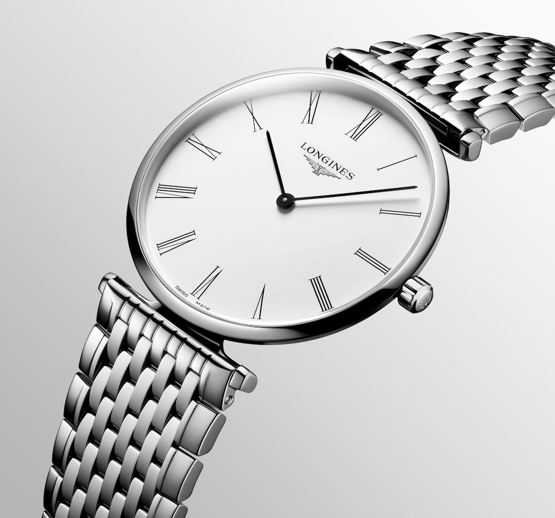 A Longines watch is displayed in the middle, angled to the right on a white background. The watch features a white dial, black hands and markers, a stainless steel bezel, and a stainless steel bracelet.