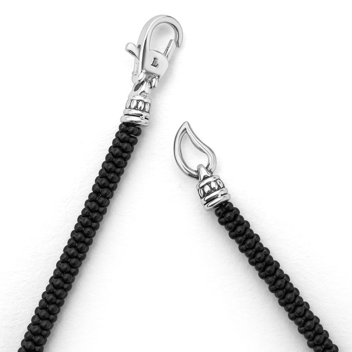 A bracelet in the middle of a white background focusing on the clasp featuring three sterling silver stations and Matte black ceramic caviar beading