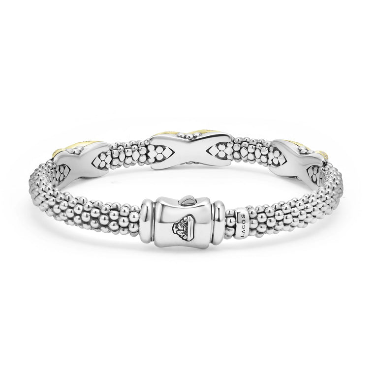 A Sterling Silver & 18k gold bracelet resting in the middle of a white background highlighting the clasp. The bracelet features diamond-set X stations, caviar beading, and a stainless steel clasp.