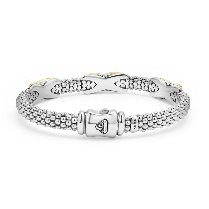 A Sterling Silver & 18k gold bracelet resting in the middle of a white background highlighting the clasp. The bracelet features diamond-set X stations, caviar beading, and a stainless steel clasp.