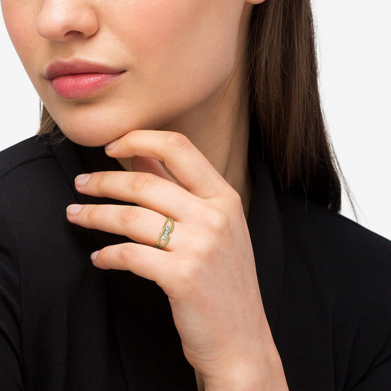 A woman wearing An 18K Gold ring in the middle of a white background featuring caviar beading and round diamonds set in the center.