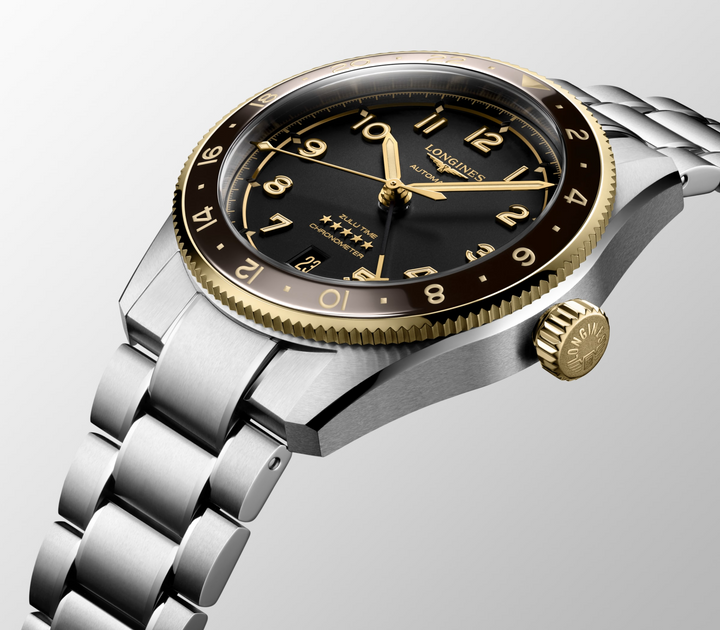 Close-up of a Longines watch, highlighting the right side profile and bracelet. The watch features a black dial, gold hands and markers, a black & gold bezel, a crown on the right side, and a stainless steel bracelet.