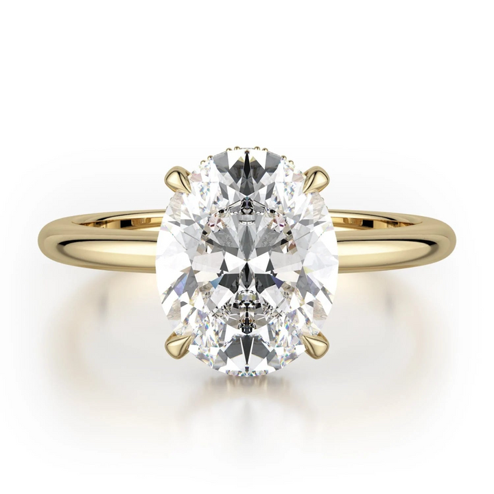 The Hidden Halo Solitaire Engagement Ring, made of yellow gold, lies flat against a white background. It features an oval-cut diamond set in the center with a diamond set hidden halo