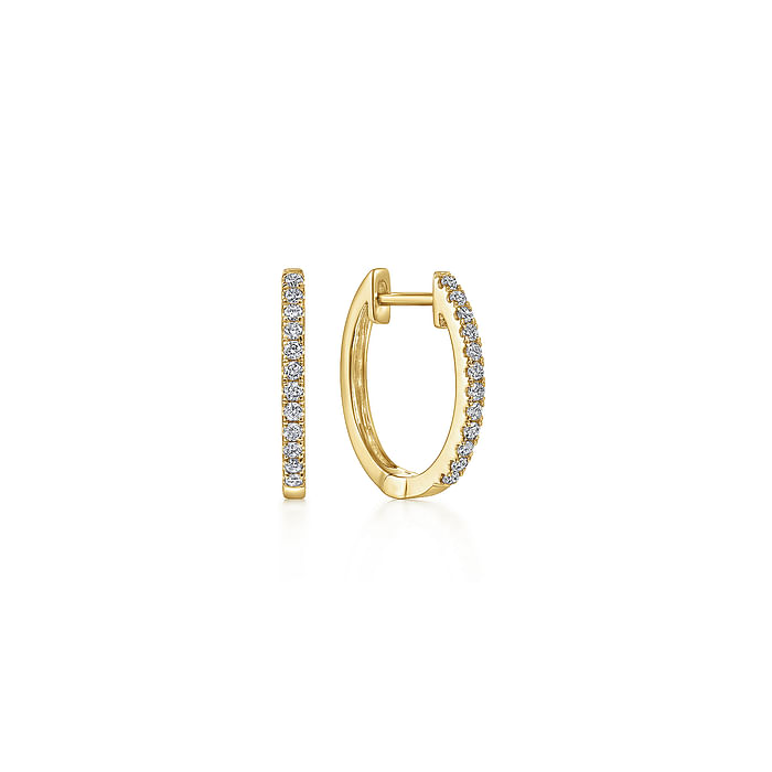 A pair of yellow-gold huggie earrings with a single row of round diamonds. The right earring is angled to the side.