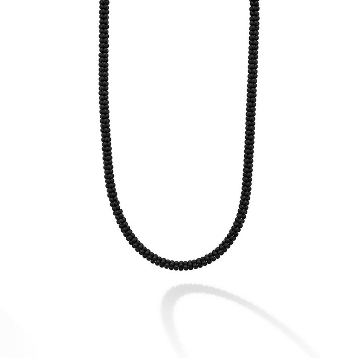 A close-up of a sterling silver and ceramic beaded necklace in the middle of a white background featuring matte black ceramic caviar beading.