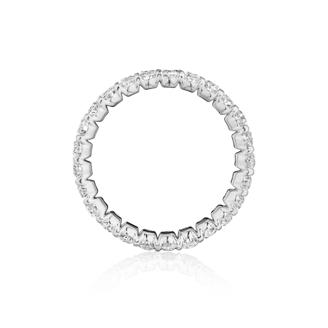 Close-up photo side-view of a white gold women's wedding band with oval cut diamonds and diamond set band on a white background