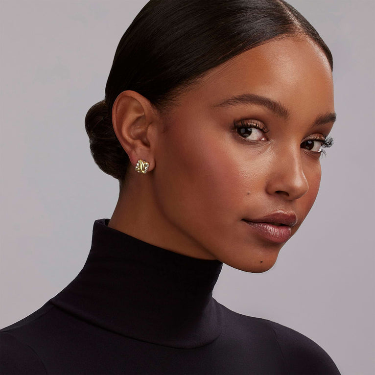 A woman is wearing a pair of two-tone earrings featuring Sterling silver and a smooth 18K gold X motif.