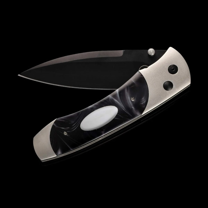 A close-up of a pocket knife with the blade out halfway. The pocket knife features an aerospace-grade titanium frame, inlays of compressed acrylic resin with an inset engraving plate, and a three-layer billet blade.