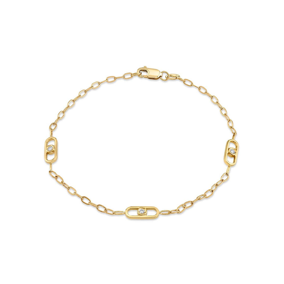 A yellow-gold bracelet lying flat against a white background. The station-style bracelet features a flat link with a bezel set diamond in the center.