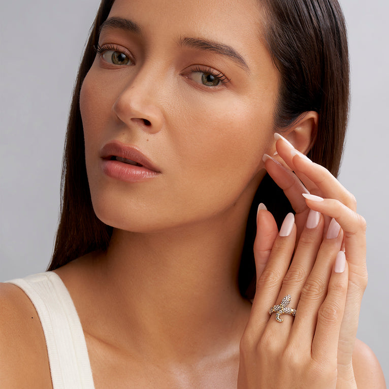 A woman is wearing a sterling silver ring featuring a snake motif with Sterling silver Caviar beading highlighted by 18K gold stations