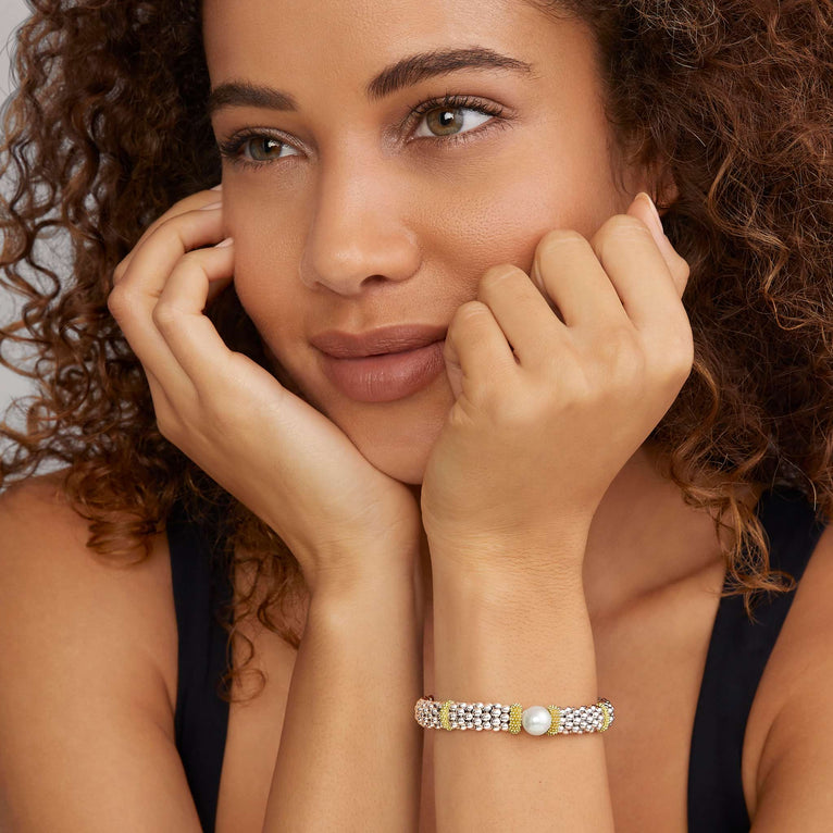 A woman wearing a Sterling silver and 18k gold bracelet featuring a freshwater cultured pearl, smooth sterling silver, Caviar beading, and 18K gold stations.