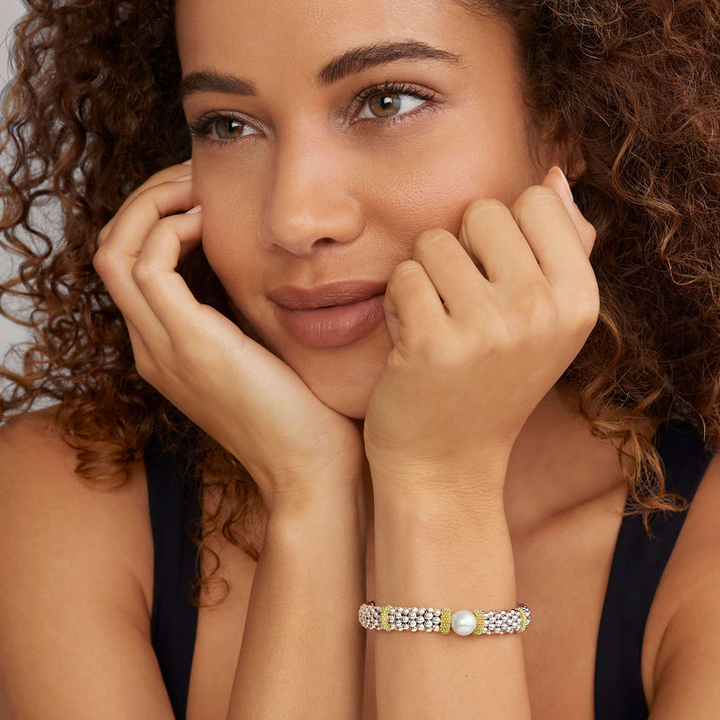 A woman wearing a Sterling silver and 18k gold bracelet featuring a freshwater cultured pearl, smooth sterling silver, Caviar beading, and 18K gold stations.