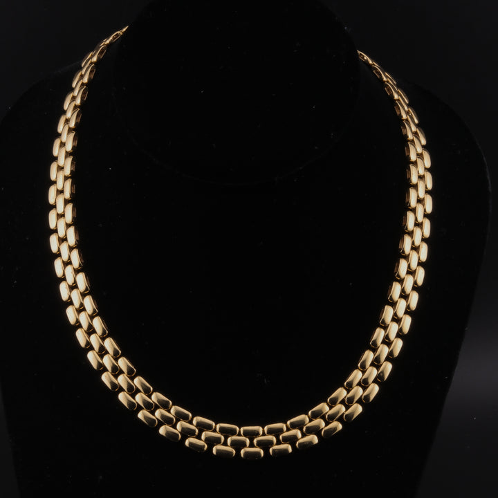 A yellow-gold necklace featuring a three-row link design against a black background.