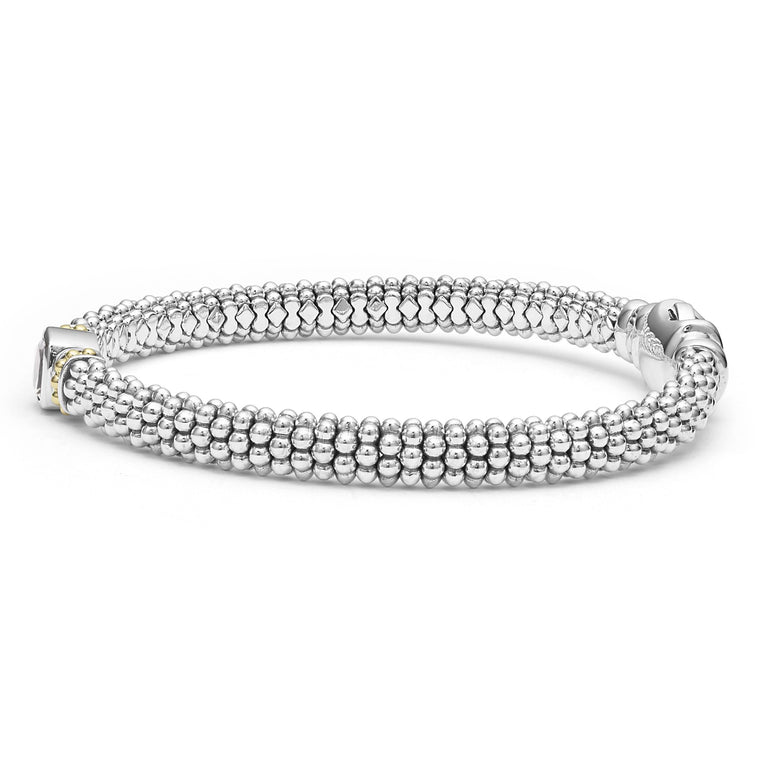 A side-view of a sterling silver bracelet in the middle of a white background features a white topaz gemstone and sterling silver Caviar beading with 18K gold detailing.