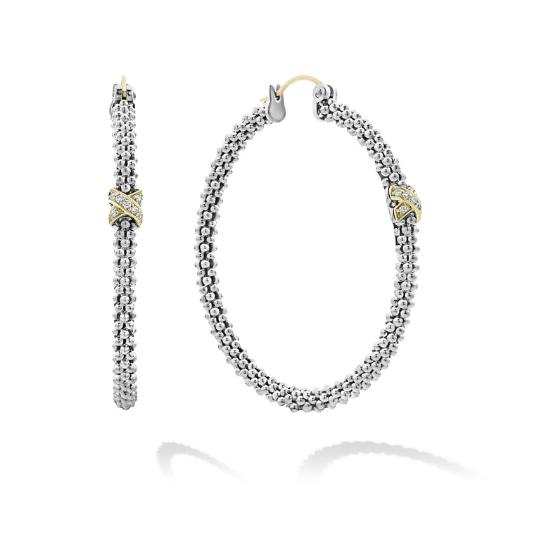 A pair of hoop earrings with a diamond and 18K gold x station with sterling silver caviar beading. The right earring is angled to the side.