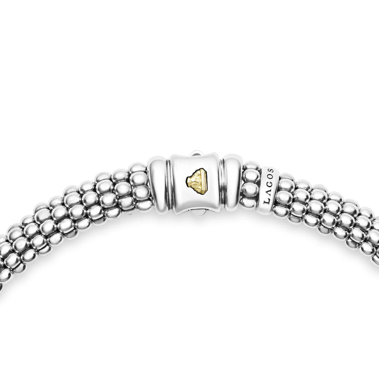 A sterling silver and 18k gold necklace in the middle of a white background, highlighting the clasp featuring white stations, one diamond set station, and caviar beading.