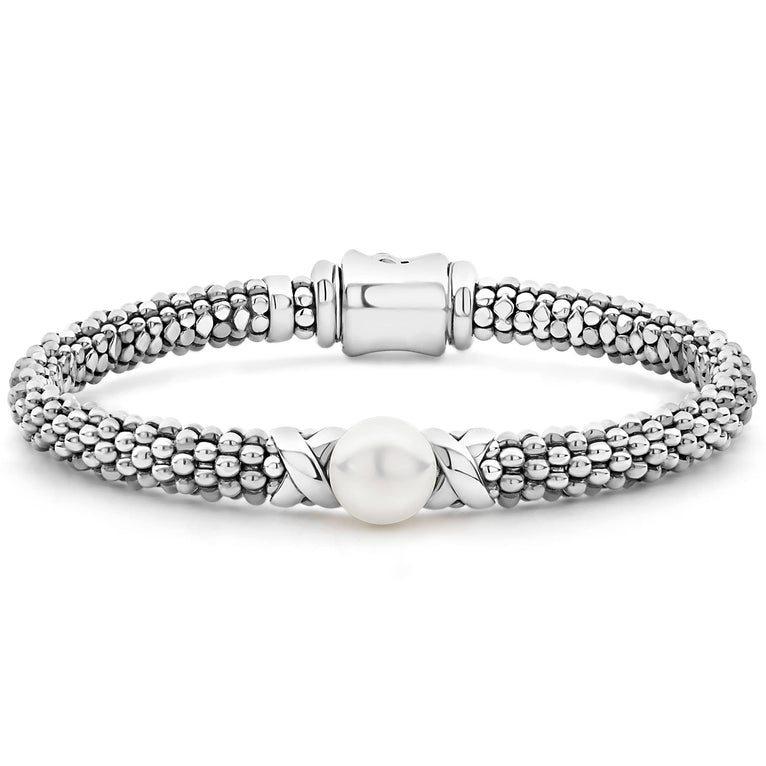 A silver bracelet in the middle of a white background featuring freshwater cultured pearl framed by two sterling silver x stations.
