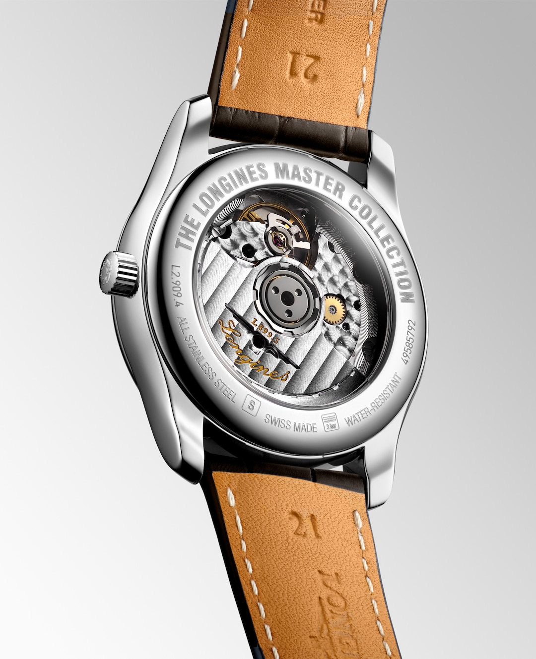 The back of a Longines watch is angled to the right, highlighting the case with an open heart design on the back and strap details. 