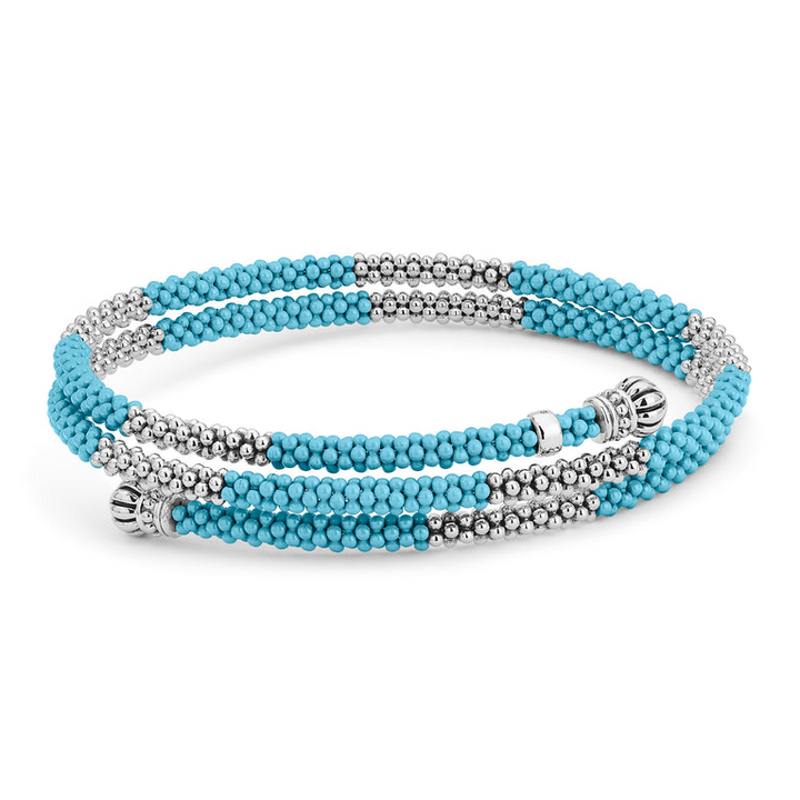 A sterling silver bracelet in the middle of a white background featuring ten sterling silver stations highlighted by blue ceramic Caviar beading finished with fluted sterling silver endcaps