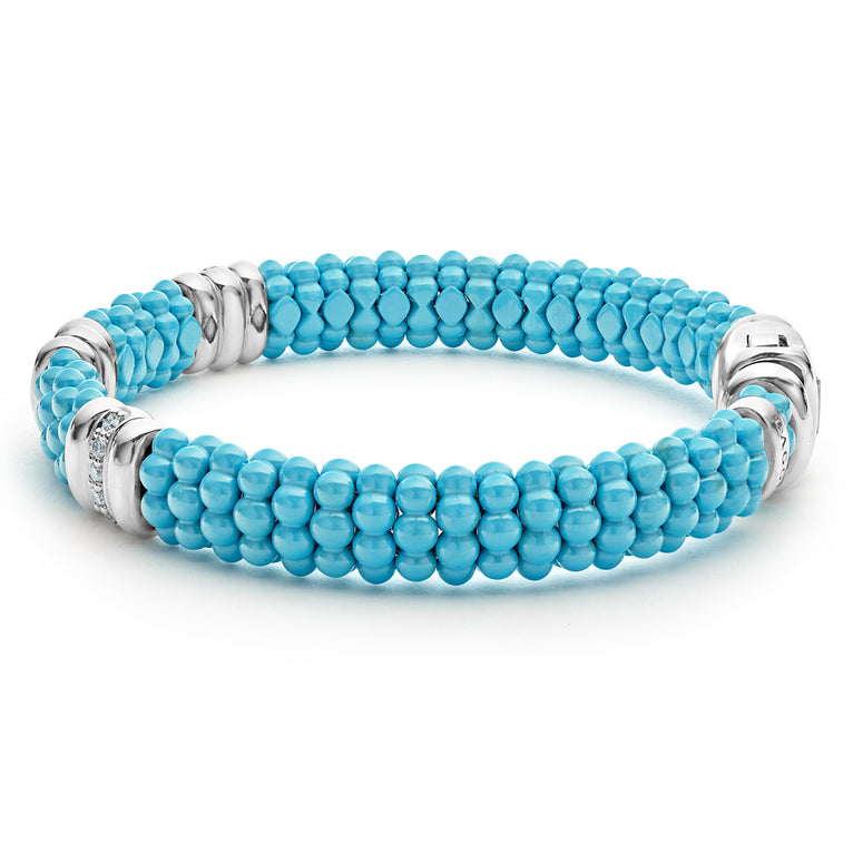 A side-view of a sterling silver bracelet in the middle of a white background featuring three diamond stations, blue ceramic caviar beading, and sterling silver stations