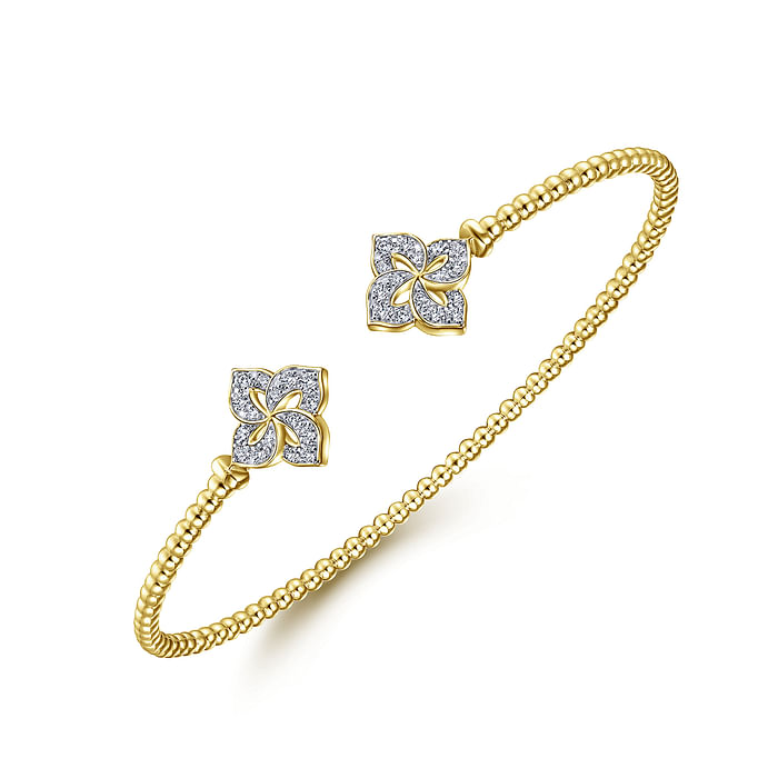 A yellow-gold bangle bracelet with a beaded band and diamond-set hibiscus motif end caps is angled in the middle of a white background.