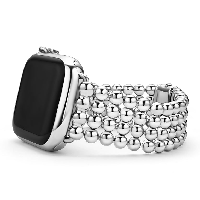 An Apple watch resting on its left side against a white background. The watch band features four rows of stainless steel beading.