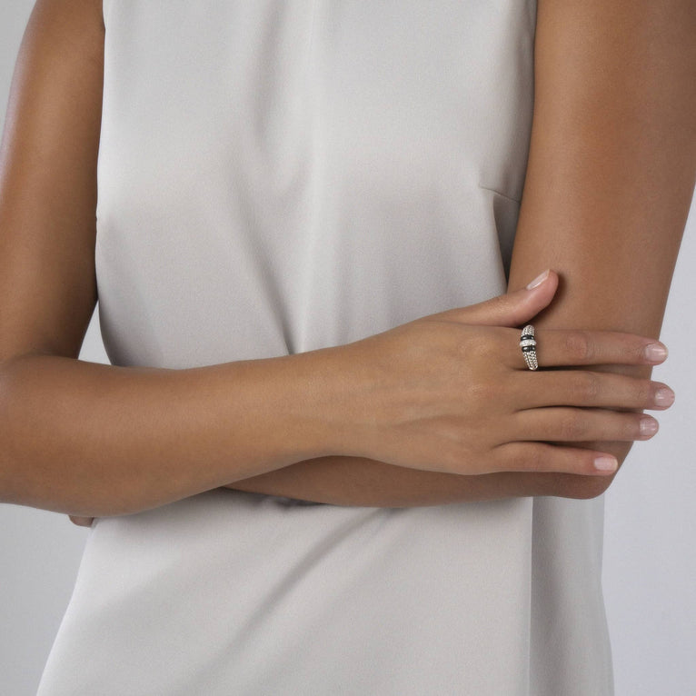 A woman is wearing a sterling silver ring featuring black ceramic caviar beading with a row of diamonds.