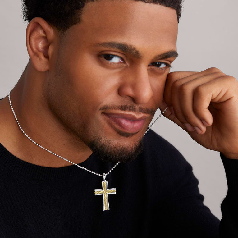 A man wearing a two-tone caviar beaded cross amulet with a chain necklace