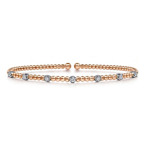 A rose gold cuff bracelet laid flat against a white background. The bracelet features round-shaped diamond stations, a rose-gold beaded band, and circle end caps.