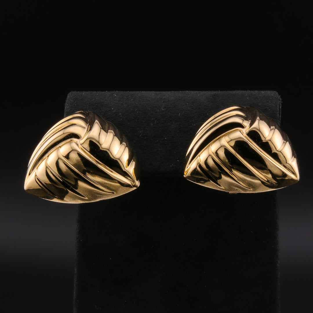 A pair of stud earrings with a shield-shaped design resting against a black background.