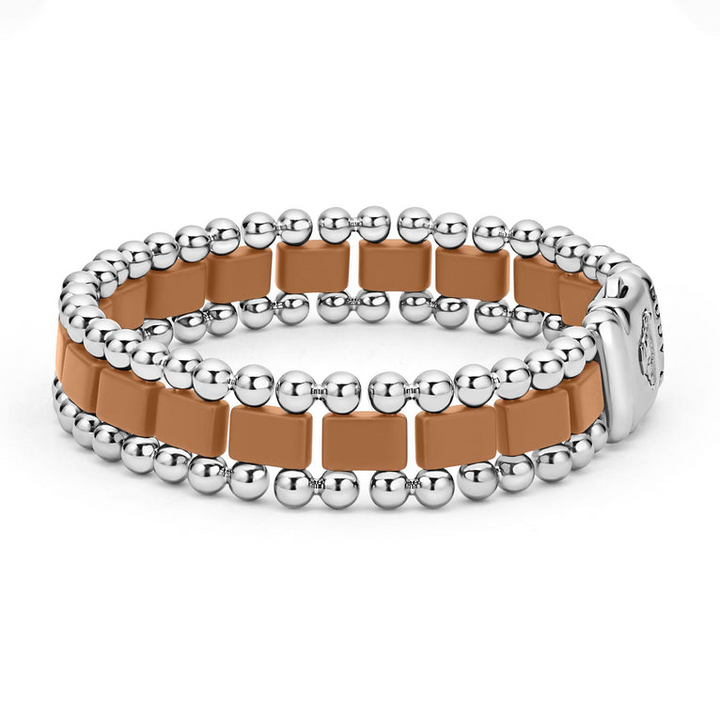 A side-view of a stainless steel bracelet in the middle of a white background featuring matte tan ceramic and caviar beading.