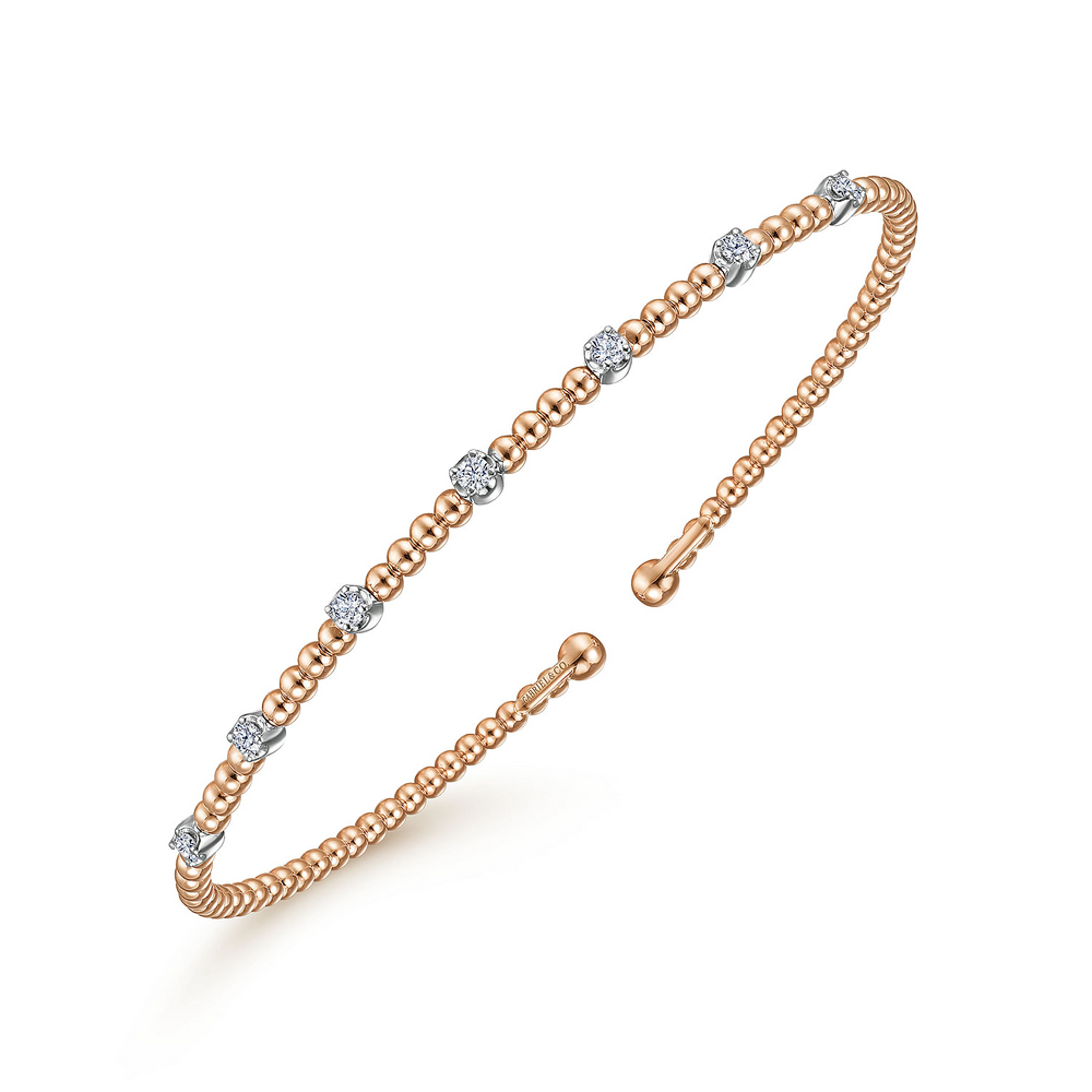 A rose-gold bangle bracelet with a beaded band, diamond stations, and end caps is angled in the middle of a white background.