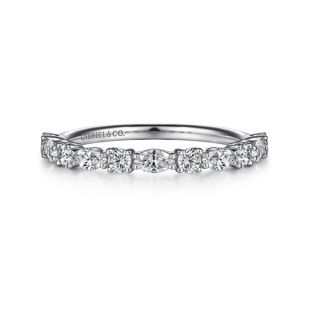 A white gold ring lies flat against a white background. The band features alternating oval and round-cut diamonds in a straight line.