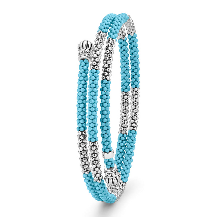 A sterling silver bracelet standing vertically in the middle of a white background featuring ten sterling silver stations highlighted by blue ceramic Caviar beading finished with fluted sterling silver endcaps