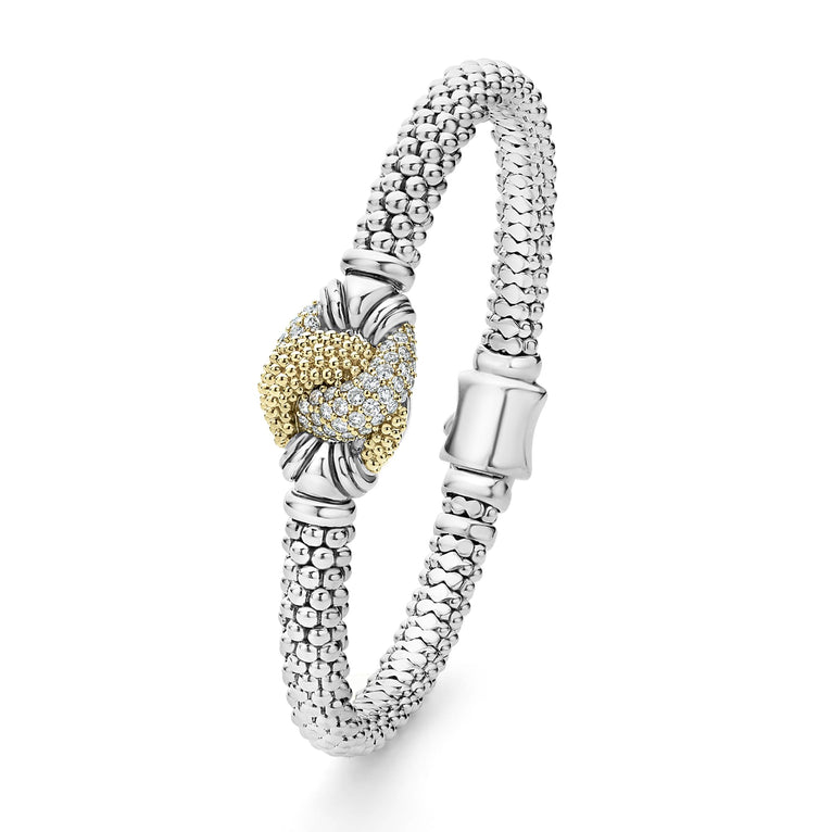 A Sterling Silver & 18k gold bracelet angled to the side resting in the middle of a white background. The bracelet features diamonds and gold women in a knot motif.