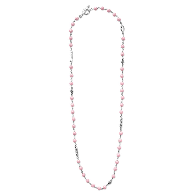 A sterling silver and ceramic beaded necklace in the middle of a white background featuring pink ceramic and silver Caviar beading.