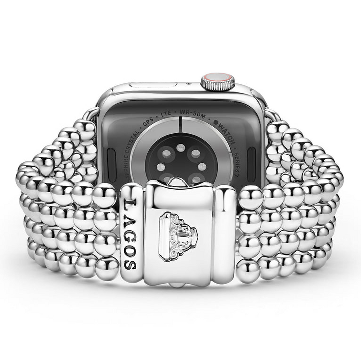 An Apple watch rests in the middle, showcasing the LAGOS engraved clasp against a white background. The watch band features four rows of stainless steel beading.