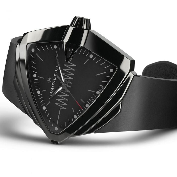 A Hamilton triangular-shaped watch is lying on its left side against a white background. It features a black dial, white hands and markers, a steel PVD black coating case, a black bezel, a steel crown, and a black rubber strap.