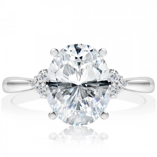 The Cluster Side Stone Engagement Ring, made of white gold, lies flat against a white background. It features an oval-cut diamond set in the center with clusters of round diamonds on the side.