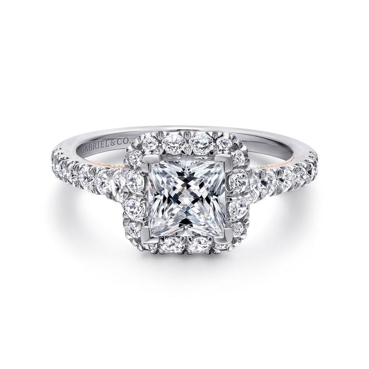 A white gold ring lies flat against a white background. It features a princess-cut diamond set in the center with a diamond halo.