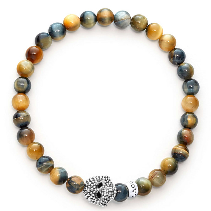 A sterling silver bracelet is displayed in the middle of a white background featuring a Tigereye gemstone beaded bracelet with a sterling silver Caviar skull.