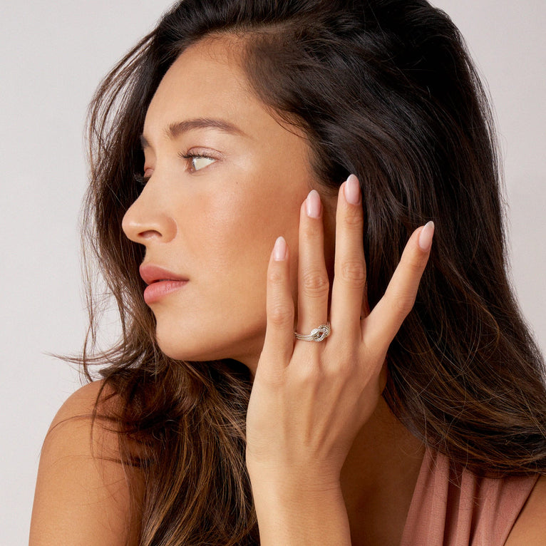 A woman is wearing a Sterling Silver & 18K Gold ring, featuring diamonds and 18K gold woven in a knot motif 