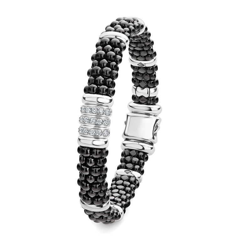 A sterling silver bracelet laid vertically in the middle of a white background featuring three diamond stations, black ceramic caviar beading, and sterling silver stations