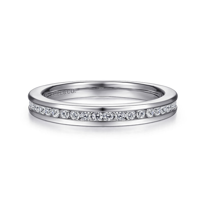 A white gold ring lies flat against a white background. The band features channel-set diamonds.