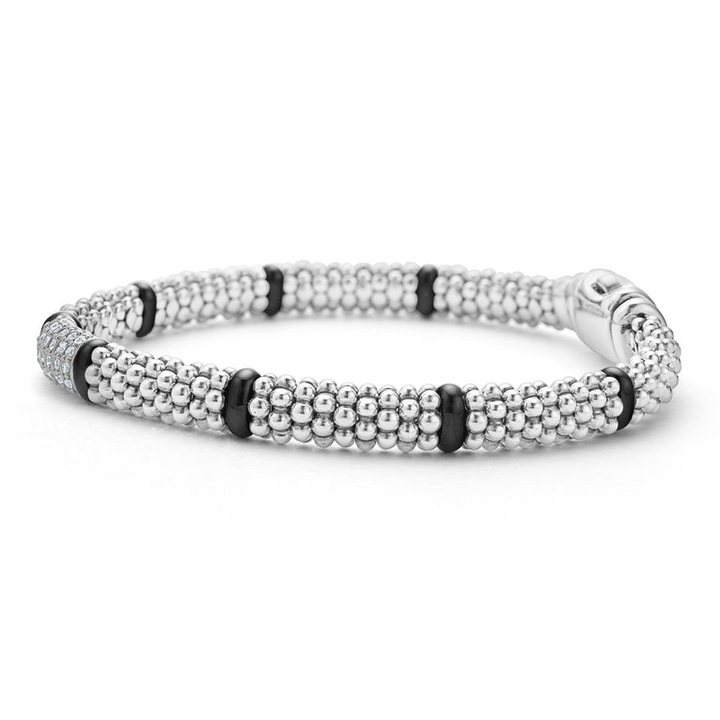 A side-view of a sterling silver bracelet in the middle of a white background features smooth black stations, diamond-set stations, and ceramic caviar beading.